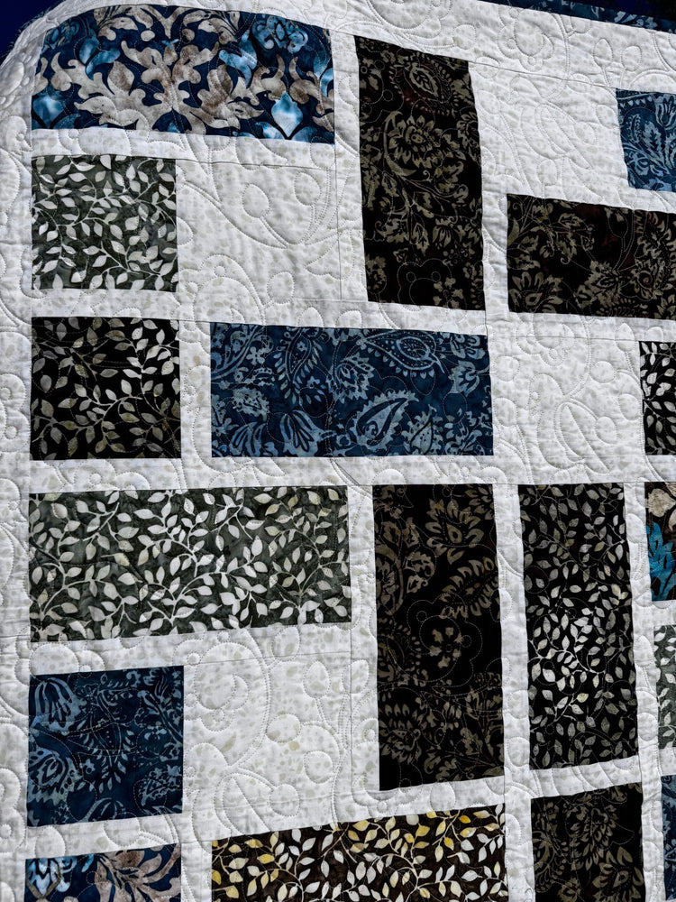 
                    
                      Quilt with a square pattern of brown, green, and aqua colored fabrics.
                    
                  