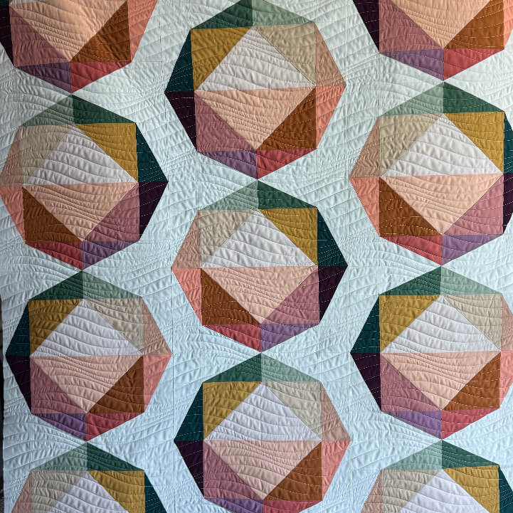 Quilt with geometric hexagonal pattern in multicolors on a white background